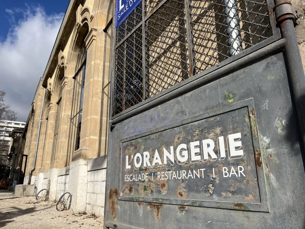 Le bâtiment de l'Orangerie de Grenoble, vu de l'extérieur, et son portail qui annonce une salle d'escalade, un restaurant et un bar
