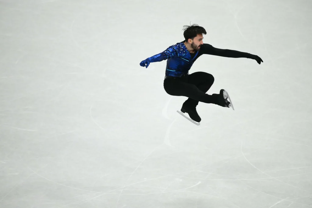Le patineur grenoblois Kevin Aymoz en plein saut sur la glace de Milan pendant son programme court