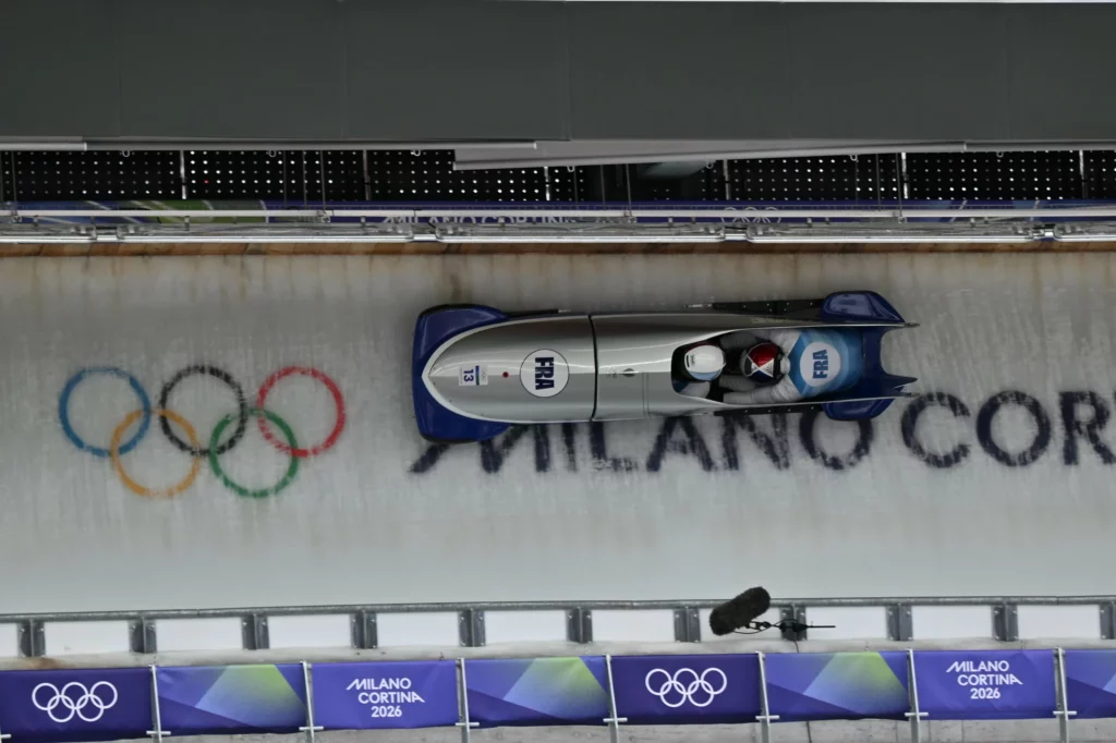Le bobsleigh de Romain Heinrich et Dorian Hauterville sur la piste de bob des Jeux olympiques de Milano-Cortina, avec les anneaux sur la piste