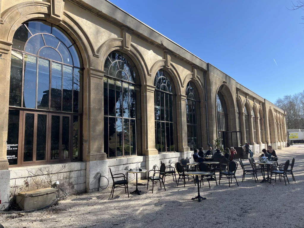 Des tables et des chaises sur la terrasse de l'orangerie de Grenoble, à l'extérieur du nouveau restaurant de la salle d'escalade