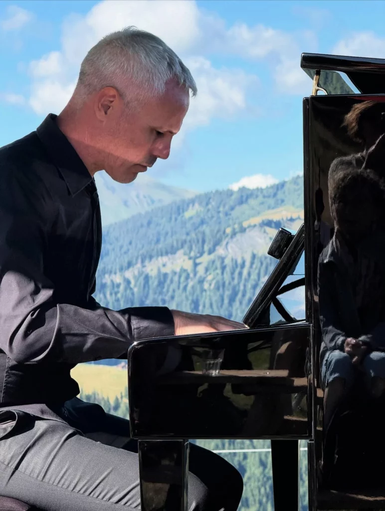 Le pianiste et accompagnateur en montage Alexandre Guhéry l'Oreille du lynx joue du piano avec la montagne pour décor