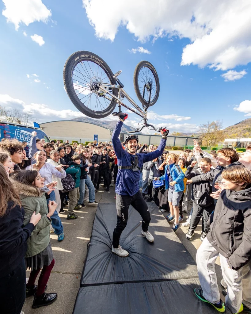 Aurélien Fontenoy lève son vélo devant des collégiens en délire