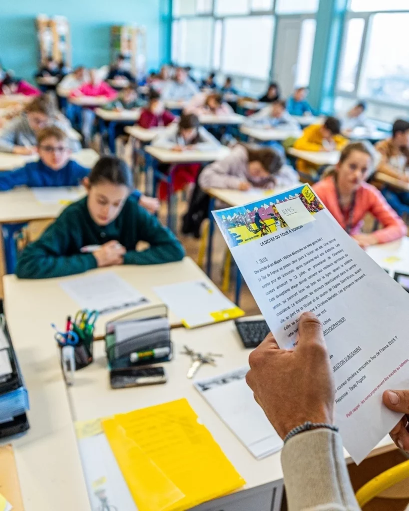 La dictée du tour de france au premier plan, les élèves en arrière-plan