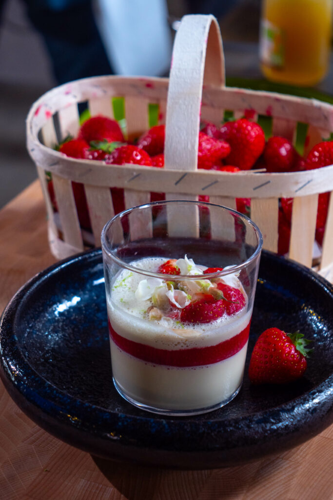 Une panna cotta aux fraises avec un panier de fraises à l'arrière-plan