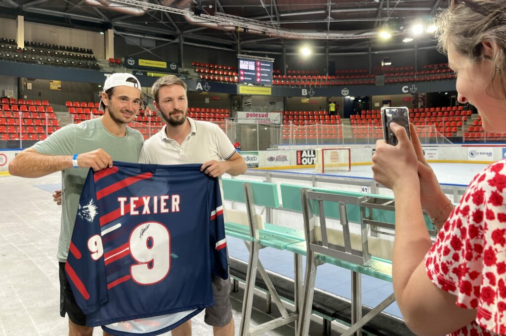 le hockeyeur grenoblois alexandre texier prend la pose avec son maillot devant une photographe à Pole Sud